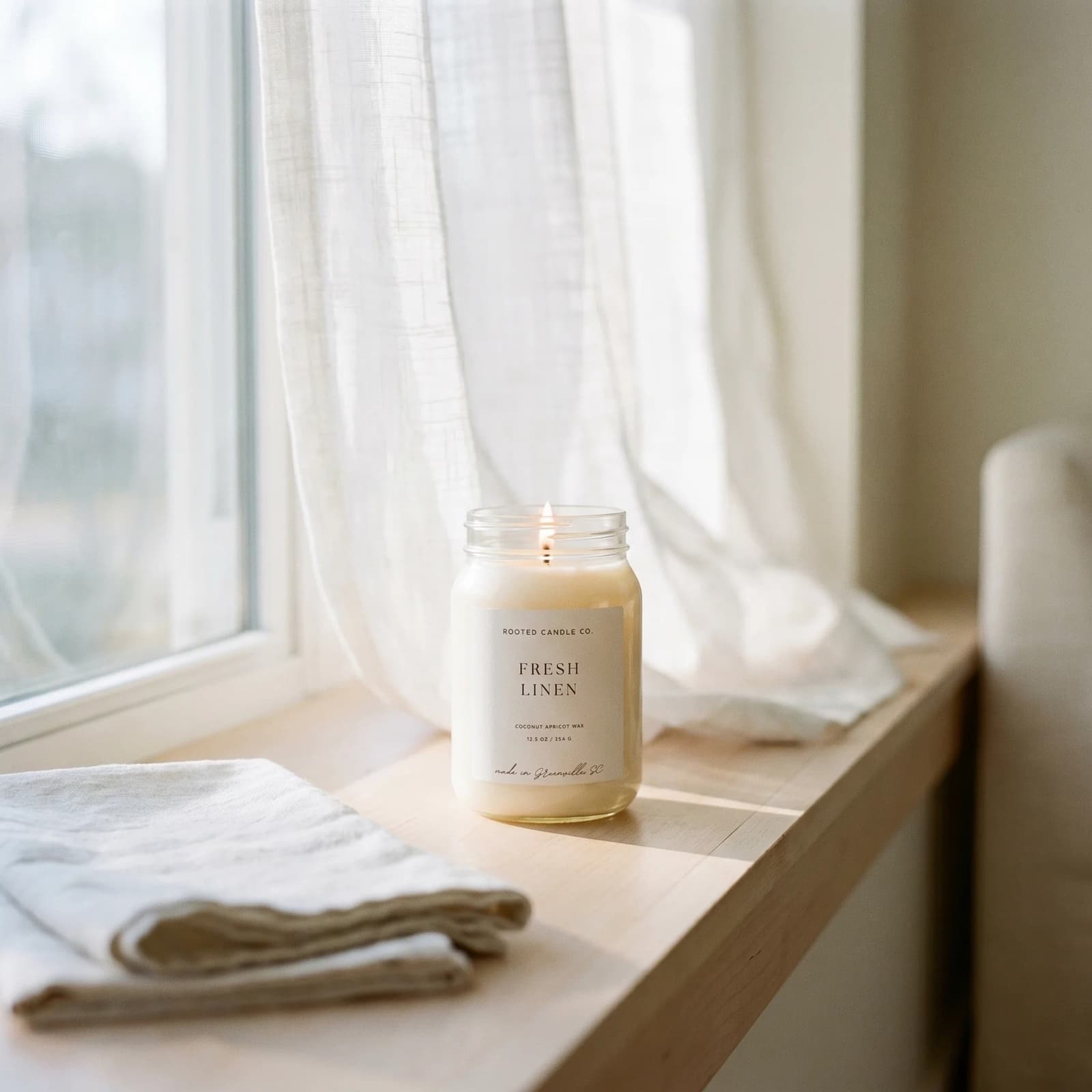 A creamy coconut apricot wax candle on a sunlit windowsill