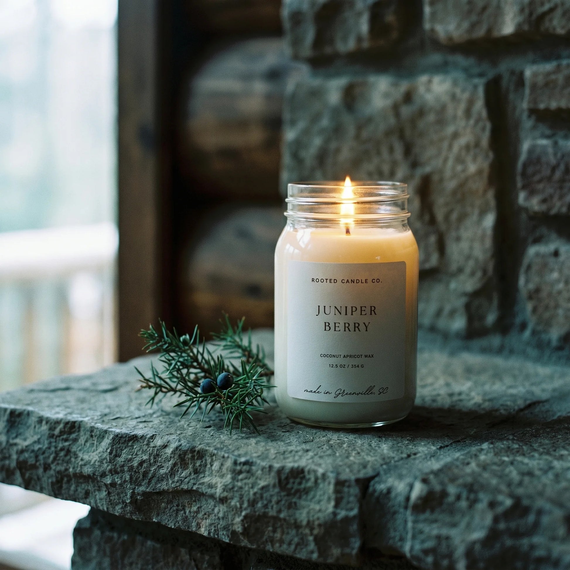 Juniper Berry candle on stone hearth with juniper sprig